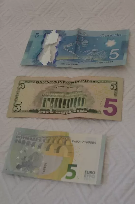 A Canadian and American $5 bill laid out with a 5 euro bill.