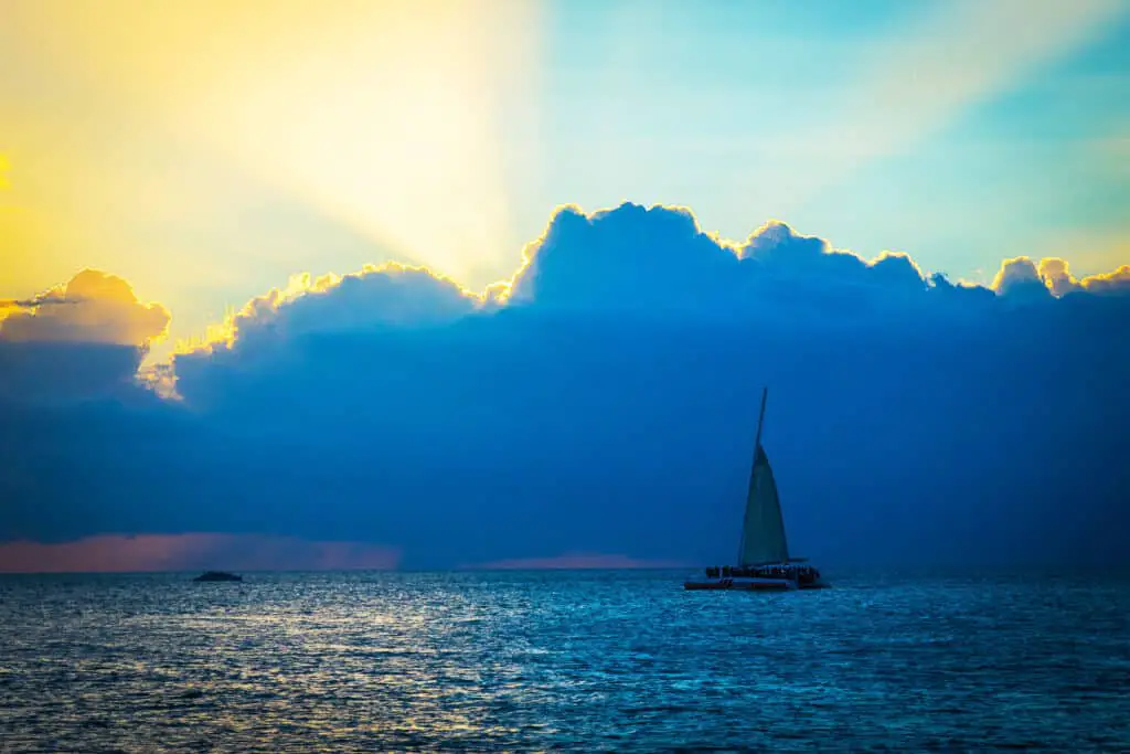 A photograph of a sailboat in front of blue and yellow clouds at sunset in Key West.