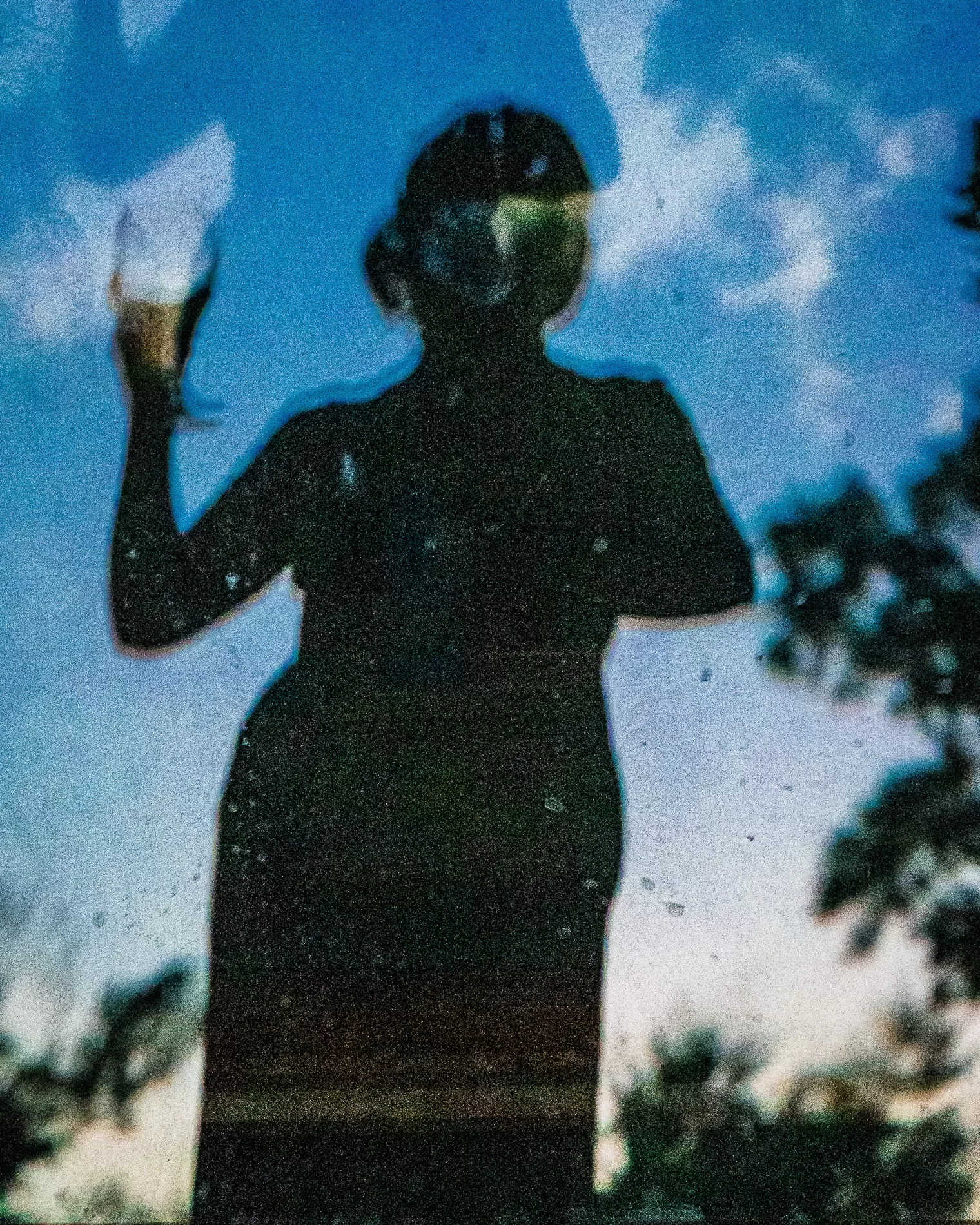 Silhouette image of a woman holding a glass of wine.